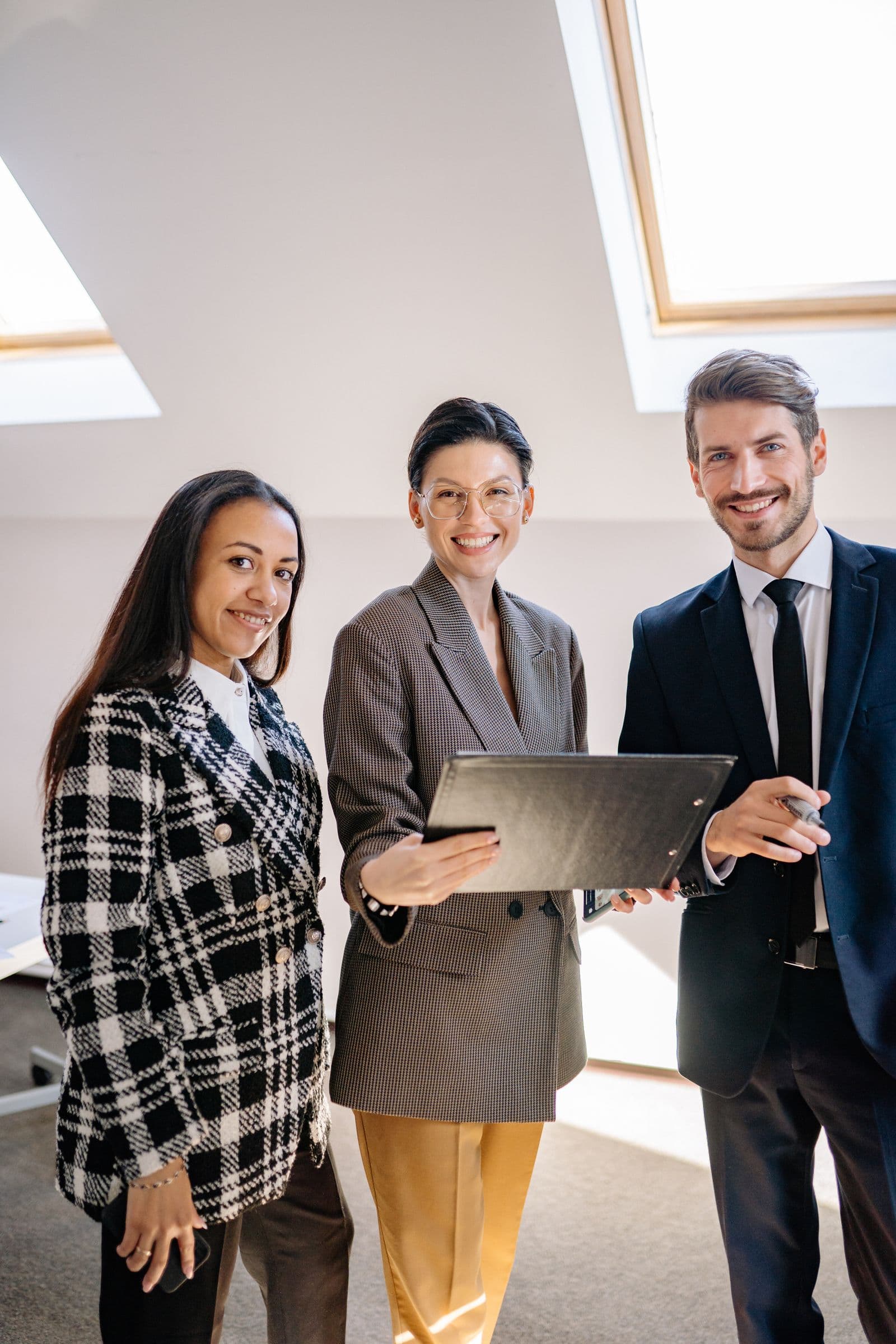 Three professionals in a bright office, looking over a folder together.